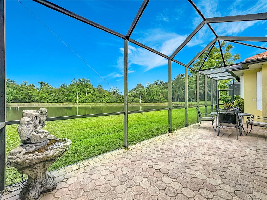 A screened-in patio with a stone fountain overlooks a grassy lawn and a pond — 8721 STONE HARBOUR LOOP, BRADENTON, FL