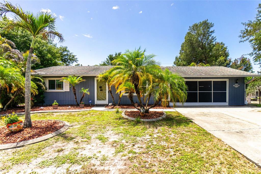 A single-story house with blue siding, a palm tree in the front yard, and a garage — 9435 BREWTON AVENUE, ENGLEWOOD, FL