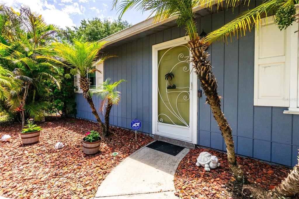 The exterior of a blue house features a light green door and palm trees — 9435 BREWTON AVENUE, ENGLEWOOD, FL