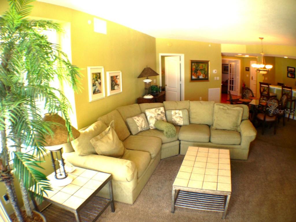 A living room features a large sectional sofa, a tiled coffee table, and a potted plant — 11 SAN MARCO STREET UNIT 504, CLEARWATER BEACH, FL