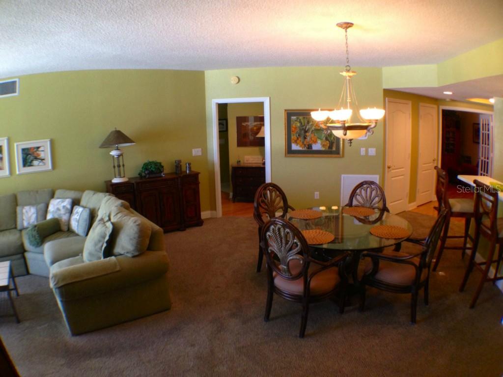A living and dining area features green walls, carpeted floors, and a glass-topped dining table — 11 SAN MARCO STREET UNIT 504, CLEARWATER BEACH, FL