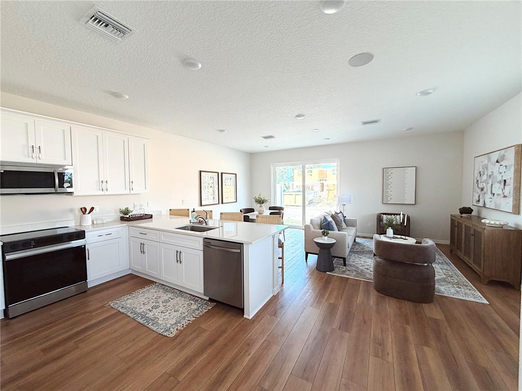 A modern kitchen features white cabinets, stainless steel appliances, and a quartz-topped island — 5839 ANGELA LEYLA PLACE, RIVERVIEW, FL
