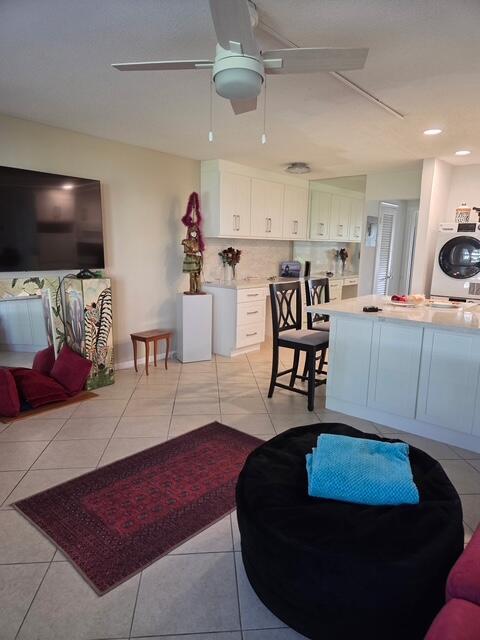 A kitchen with white cabinetry, a center island, and a tiled floor opens to a living area — 460 Horizons W # 111, Boynton Beach FL 33435, BOYNTON BEACH, FL