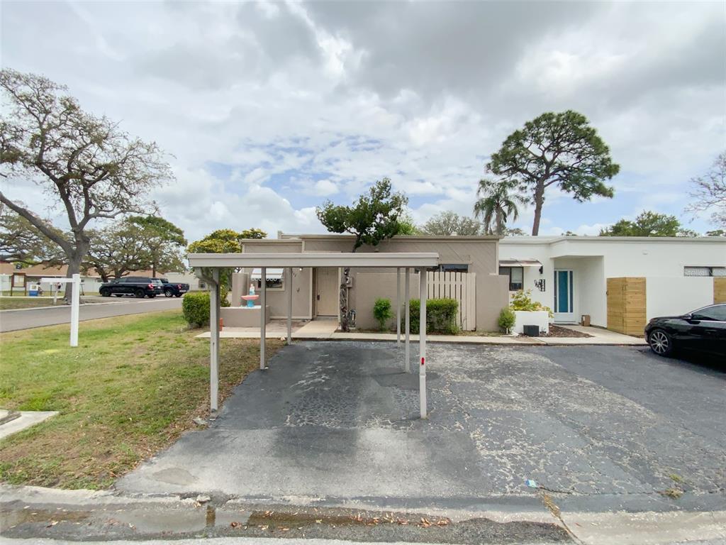 A single-story house with a carport and a paved driveway under a cloudy sky — 2242 PINEWOOD VILLAS DRIVE, HOLIDAY, FL