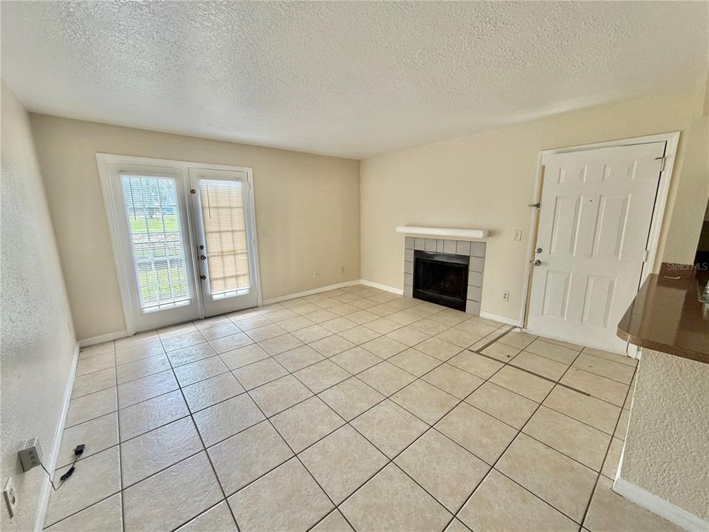 A living room features light tile flooring, a fireplace, and glass doors leading outside — 2550 N ALAFAYA TRAIL UNIT 3103, ORLANDO, FL