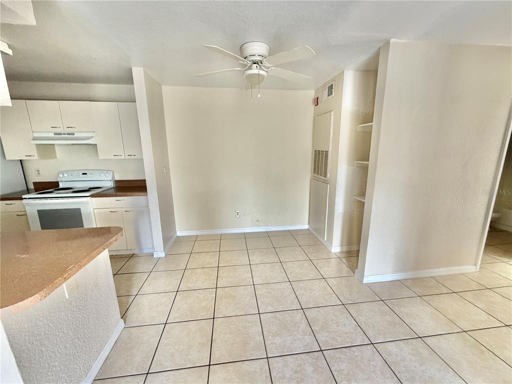 A dining area features tile flooring, a ceiling fan, and an adjacent kitchen with white cabinets — 2550 N ALAFAYA TRAIL UNIT 3103, ORLANDO, FL