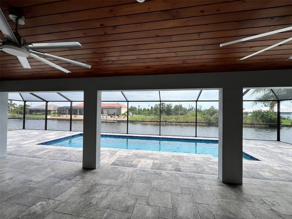 An aerial view of a house with a screened-in pool overlooking a canal at sunset — 15267 APPLETON BOULEVARD, PORT CHARLOTTE, FL