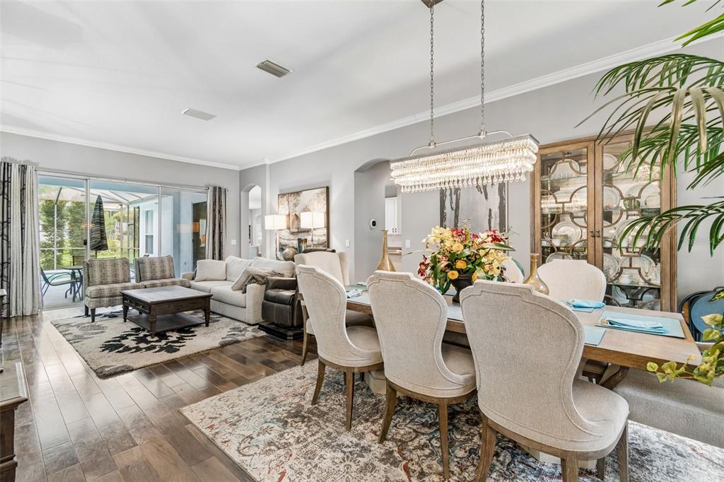An open-concept dining and living area features hardwood floors, a crystal chandelier, and sliding doors — 2005 WEXFORD GREEN DRIVE, VALRICO, FL