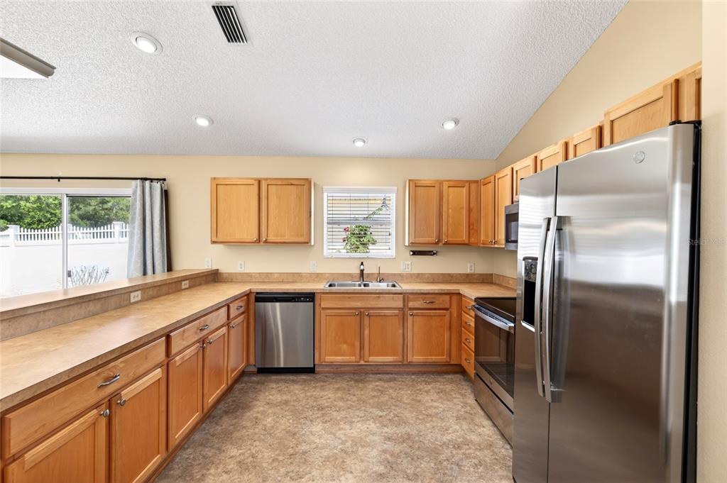 A kitchen features light wood cabinets, stainless steel appliances, and a laminate countertop — 430 CALVERT TERRACE, THE VILLAGES, FL
