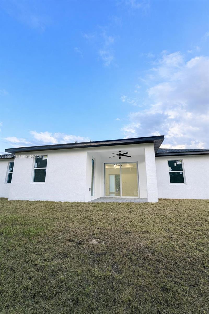 The exterior view shows the back of a white house with a covered patio — 3901 E 19th St, Lehigh Acres FL 33972, LEHIGH ACRES, FL