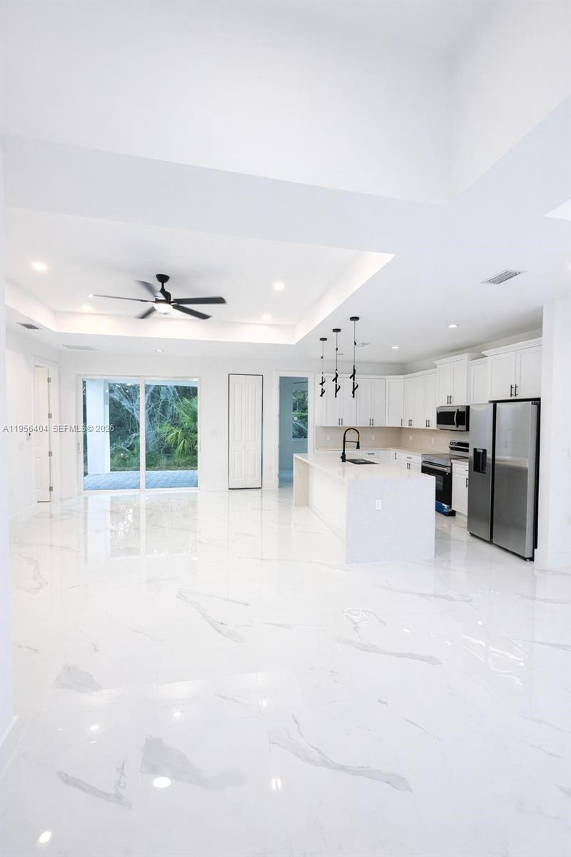 A modern open-concept kitchen and living area features white marble floors and high ceilings — 3901 E 19th St, Lehigh Acres FL 33972, LEHIGH ACRES, FL