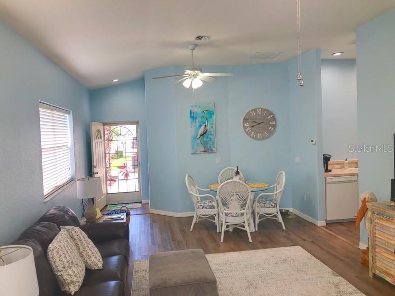 A living and dining area features light blue walls, wood-look flooring, and a ceiling fan — 1211 HOT SPRINGS POINT, ENGLEWOOD, FL