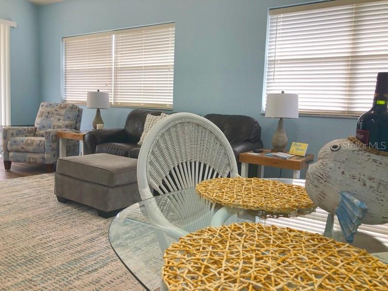 A living room features a glass dining table, a leather sofa, and a patterned armchair — 1211 HOT SPRINGS POINT, ENGLEWOOD, FL