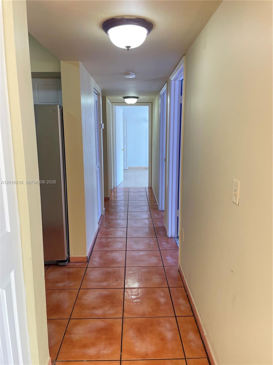 A hallway with terracotta tile flooring leads to an open doorway at the end — 6255 Kendale Lakes Cir # 116, Miami FL 33183, MIAMI, FL