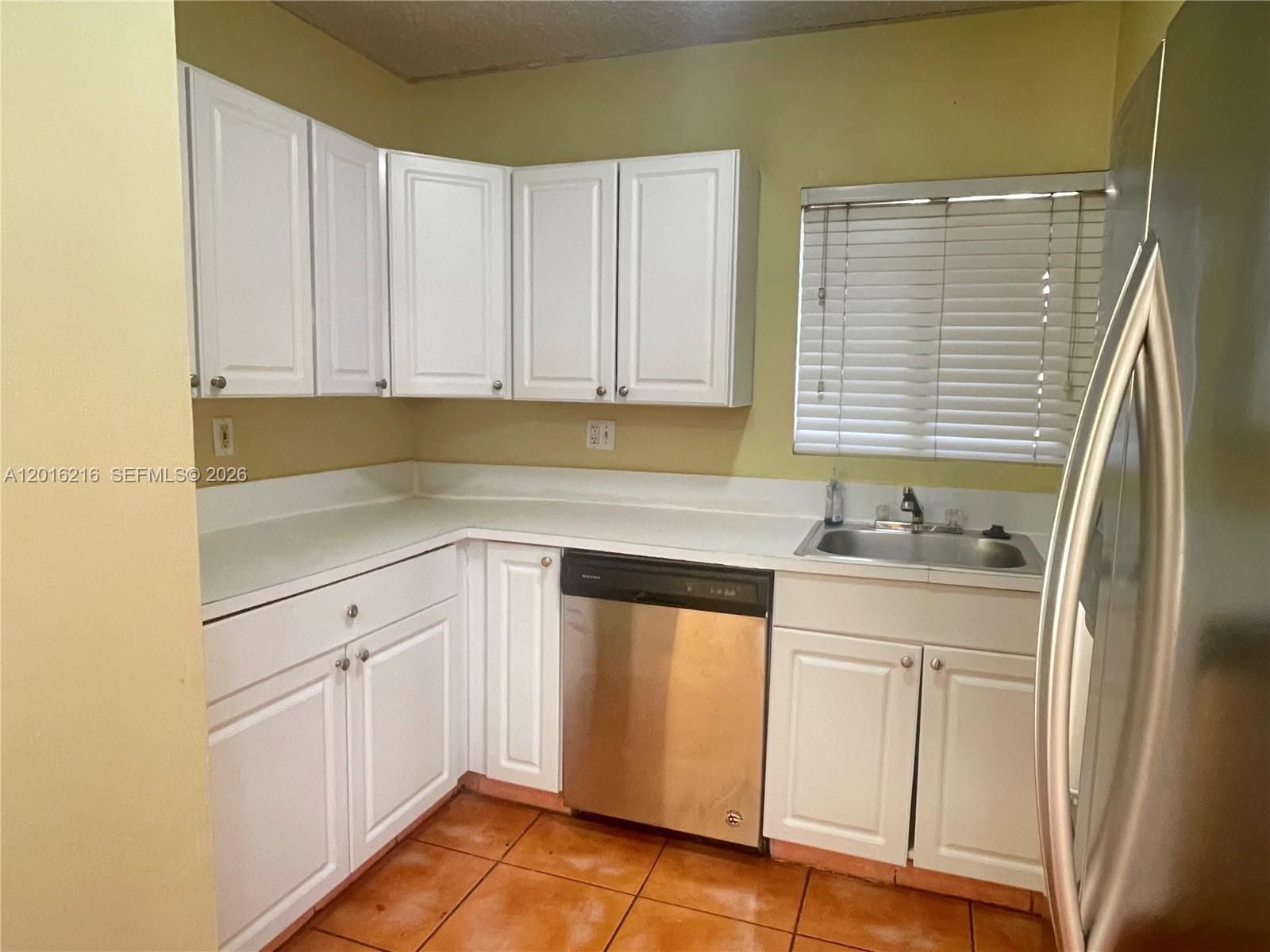 A kitchen features white cabinets, stainless steel appliances, a sink, and orange tile flooring — 6255 Kendale Lakes Cir # 116, Miami FL 33183, MIAMI, FL