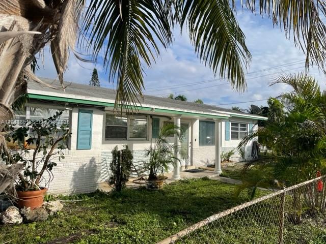 A single-story white brick house with a green roof trim and blue window shutters — WEST PARK, FL