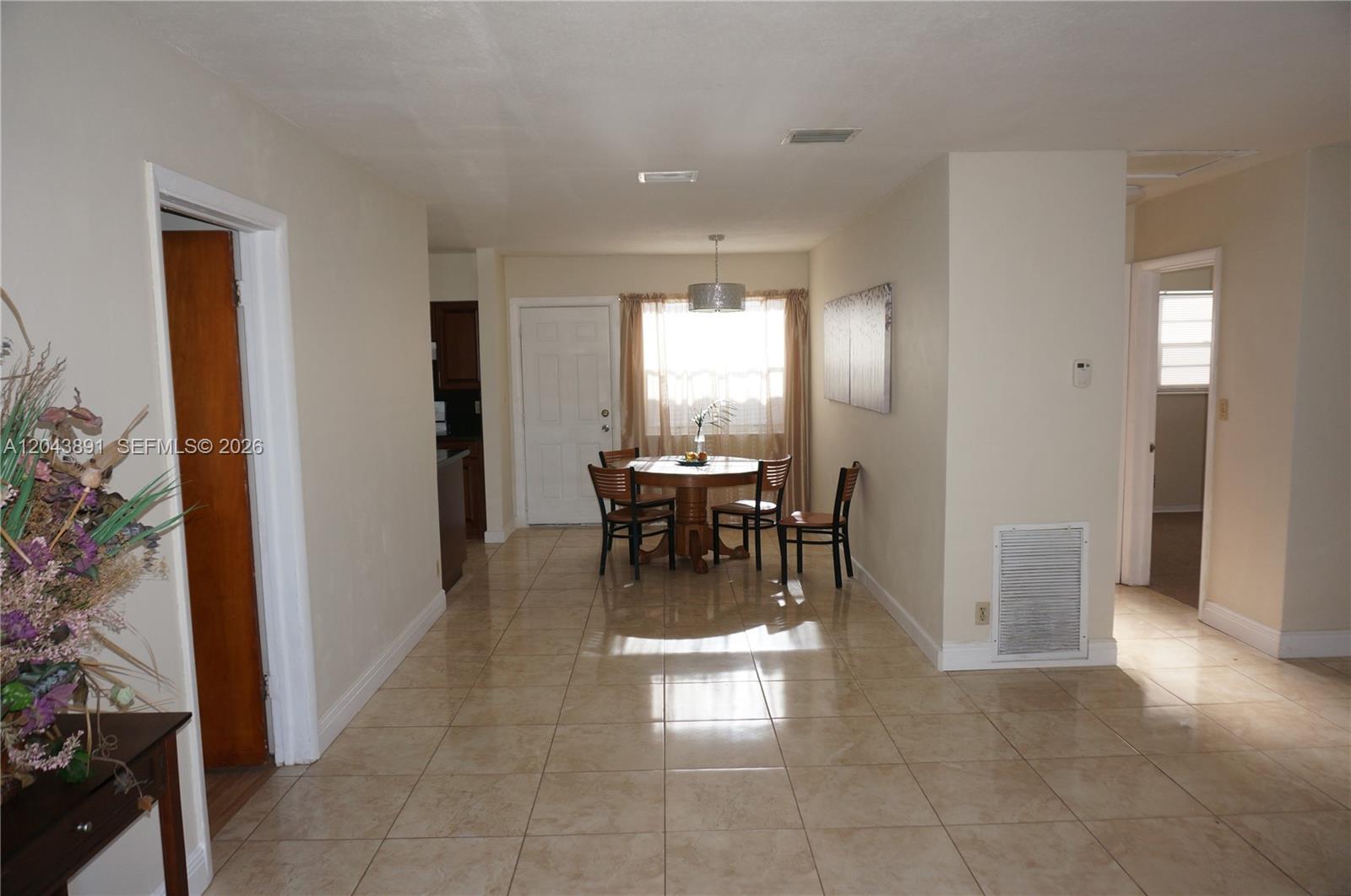 A dining area features a round wooden table, four chairs, and light-colored tile flooring — WEST PARK, FL