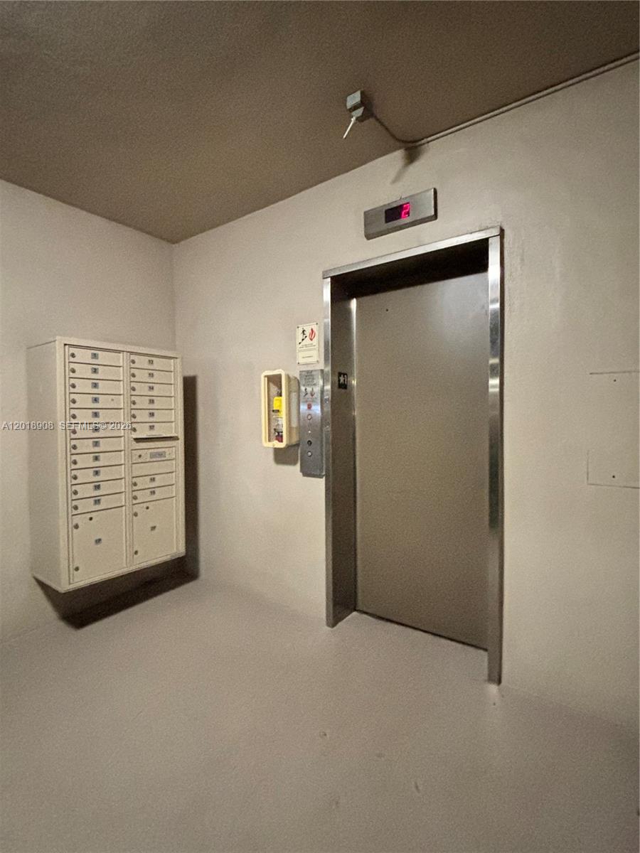 An elevator and a wall-mounted mail unit are located in a plain, neutral-colored hallway — 1480 E Sample Rd # 209, Pompano Beach FL 33064, POMPANO BEACH, FL