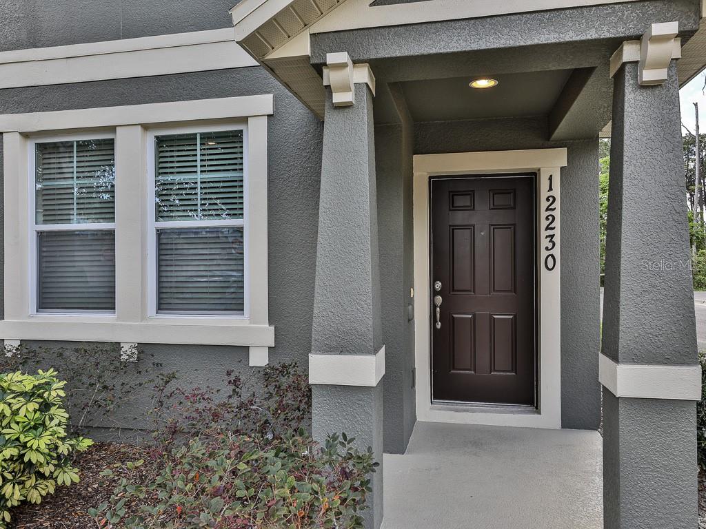 A dark brown front door with vertical house numbers sits under a covered porch entrance — 12230 LANGSTAFF DRIVE, WINDERMERE, FL