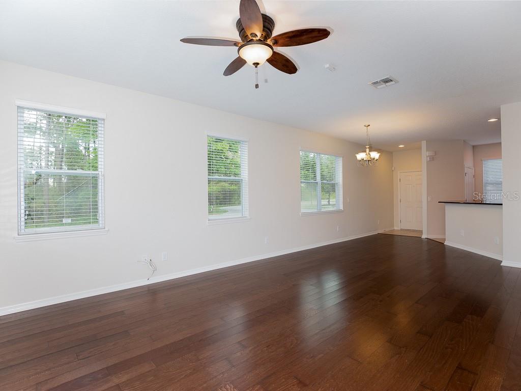 An open-concept living area features dark hardwood floors, white walls, and a ceiling fan — 12230 LANGSTAFF DRIVE, WINDERMERE, FL