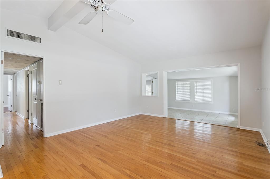 An empty living room features hardwood floors, a vaulted ceiling with a fan, and tile flooring — 508 DUNBLANE DRIVE, WINTER PARK, FL