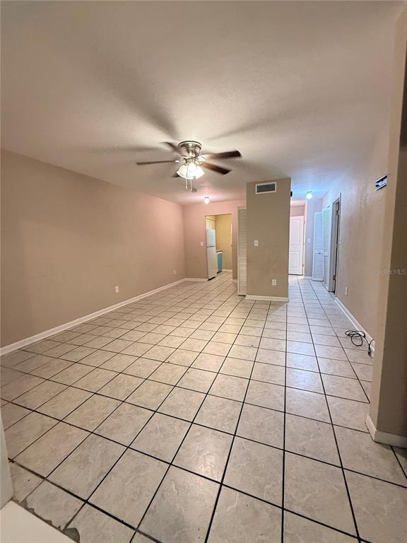 An open-concept room features light-colored tile flooring, beige walls, and a ceiling fan — 1721 SW 68TH TERRACE UNIT 1721, GAINESVILLE, FL