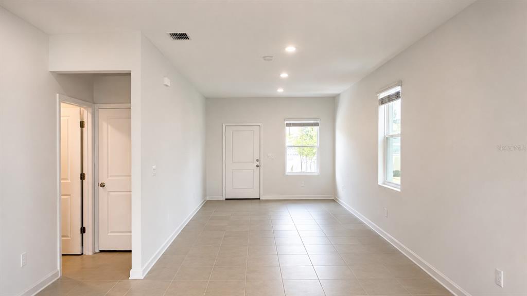 An empty room with light-colored tile flooring, white walls, recessed lighting, and two windows — 6069 ZEN WAY, CLERMONT, FL