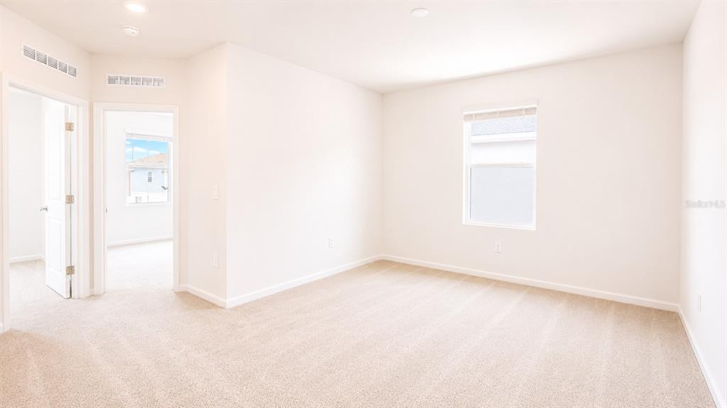 An empty bedroom features beige carpeting, white walls, a single window, and an open doorway — 6069 ZEN WAY, CLERMONT, FL