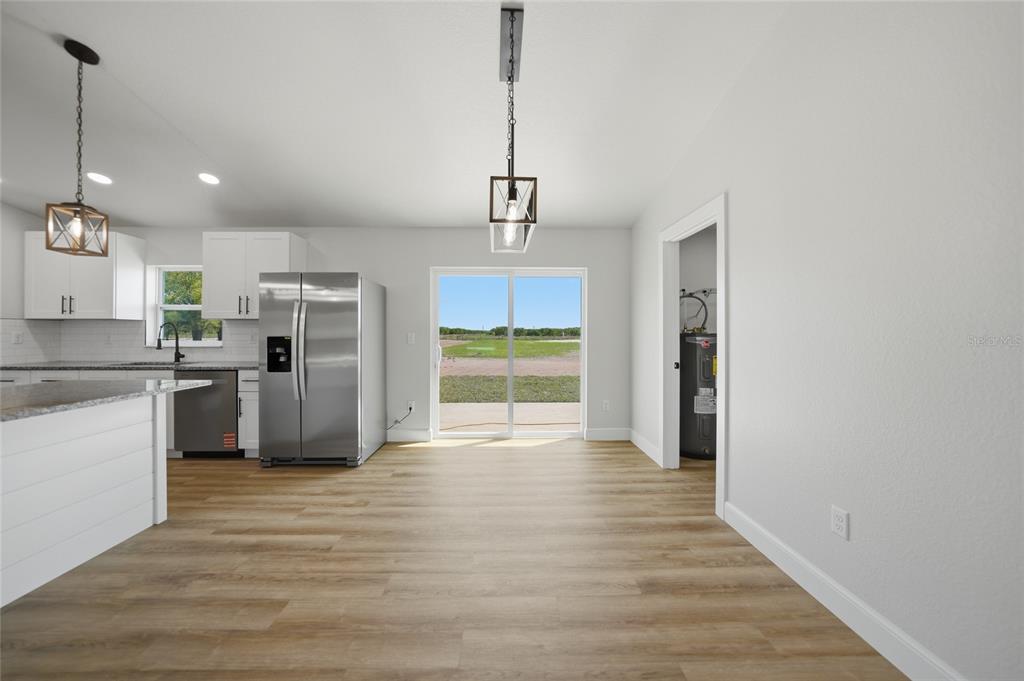 A kitchen and dining area with white cabinets, stainless steel appliances, and wood-look flooring — 6894 SW MIAMI AVENUE, ARCADIA, FL