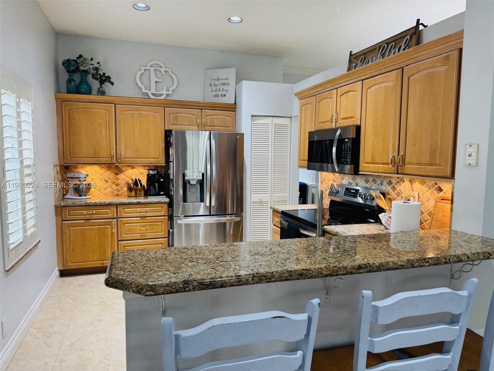 A kitchen features oak cabinets, granite countertops, stainless steel appliances, and a breakfast bar — 4321 Willow Ridge Dr, Weston FL 33331, WESTON, FL