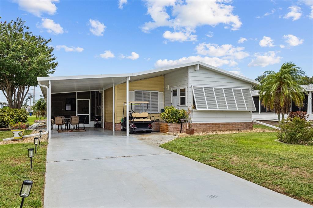 A single-story manufactured home features a concrete driveway, a carport, and light-colored siding — 713 TANGERINE WOODS BOULEVARD, ENGLEWOOD, FL