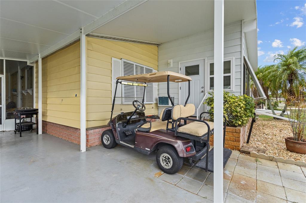 A golf cart is parked under a covered carport next to a house with siding — 713 TANGERINE WOODS BOULEVARD, ENGLEWOOD, FL
