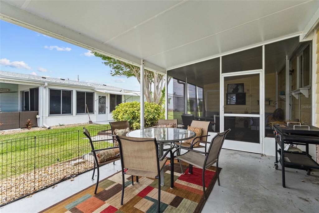 A covered patio features a glass-top dining set on a rug and a screened enclosure — 713 TANGERINE WOODS BOULEVARD, ENGLEWOOD, FL