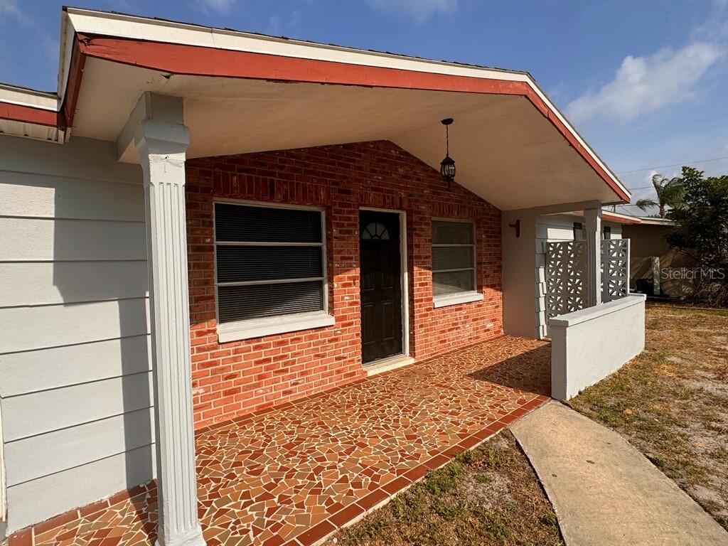 A brick-front house features a covered porch with a mosaic tile floor and white columns — 10731 PREMIER AVENUE, PORT RICHEY, FL