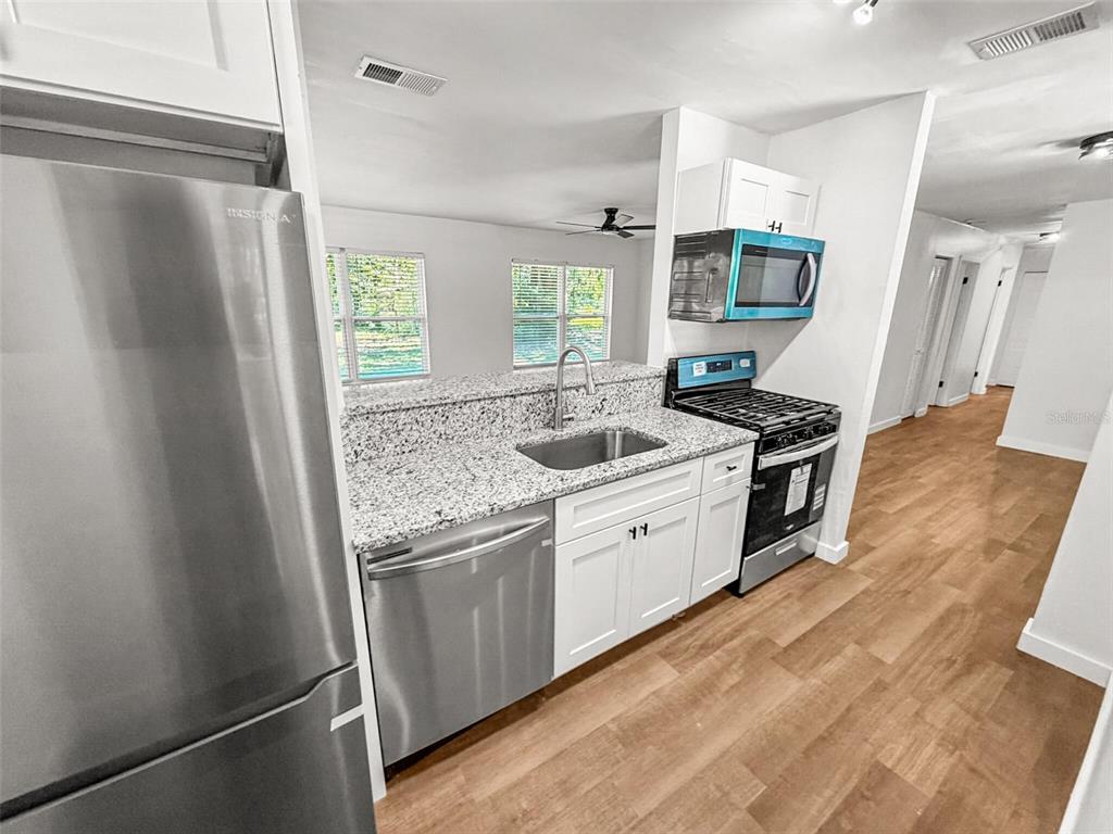 A kitchen features stainless steel appliances, white cabinets, and granite countertops with a sink — 2532 NE 13TH AVENUE, GAINESVILLE, FL