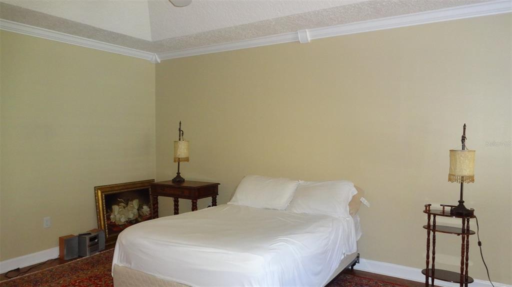 A bedroom with beige walls, a white bed, and two side tables with lamps — 1144 DELANEY AVENUE UNIT 1144, ORLANDO, FL