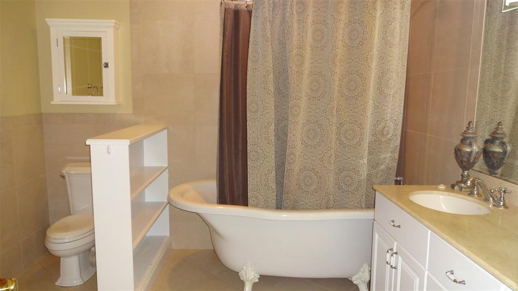 A bathroom features a clawfoot tub, a white vanity, a toilet, and a shelving unit — 1144 DELANEY AVENUE UNIT 1144, ORLANDO, FL
