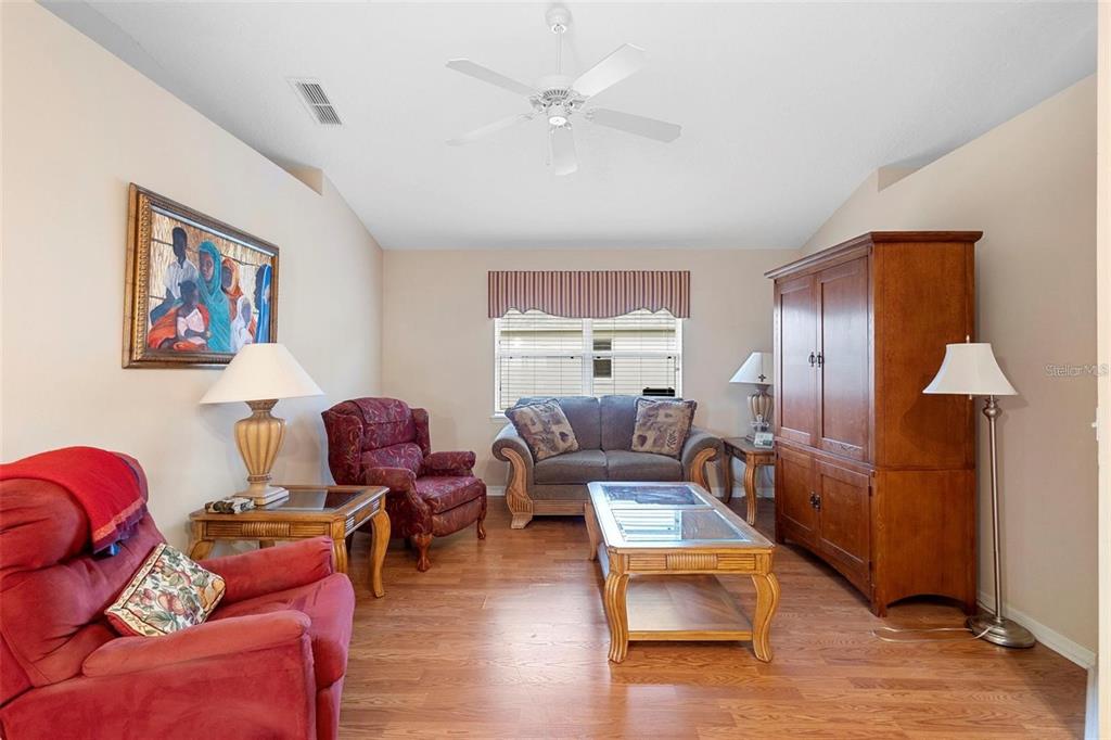 A living room features hardwood floors, a ceiling fan, a sofa, and several armchairs — 713 MOUNTAIN ASH WAY, DELTONA, FL