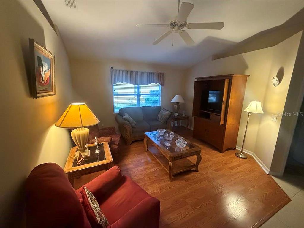 A living room features hardwood floors, a ceiling fan, a sofa, and a wooden armoire — 713 MOUNTAIN ASH WAY, DELTONA, FL