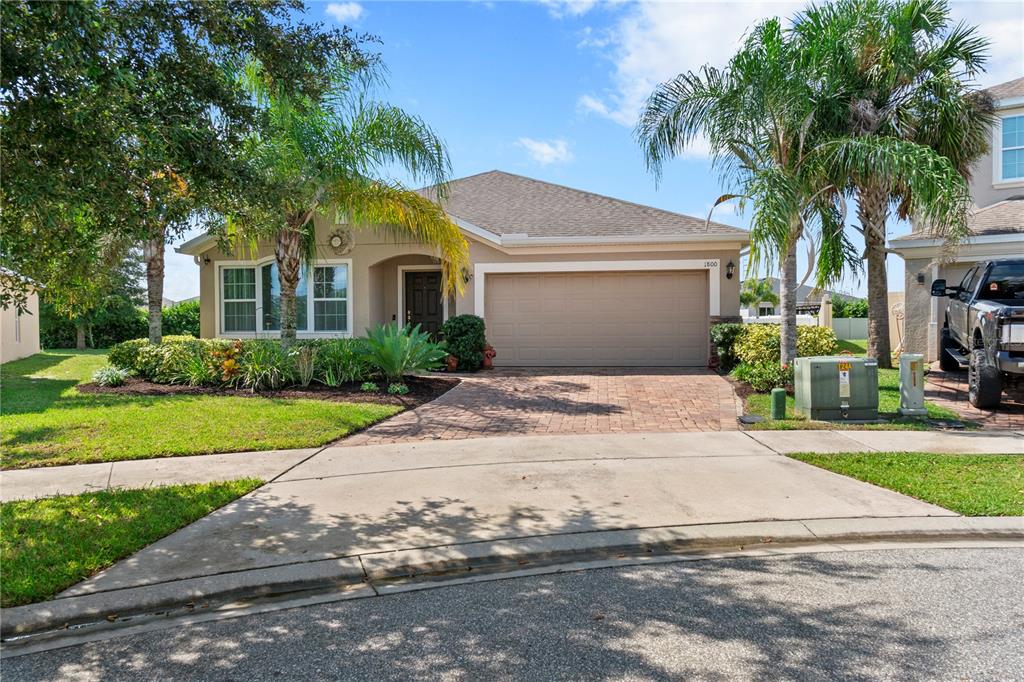 A single-story house with a beige exterior, a two-car garage, and a paved driveway — 1800 STILLWOOD WAY, ST CLOUD, FL