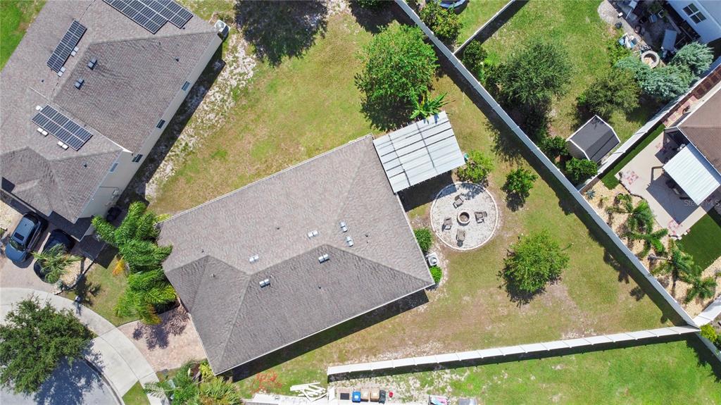 An aerial view shows a house with a shingled roof, solar panels, and backyard patio — 1800 STILLWOOD WAY, ST CLOUD, FL
