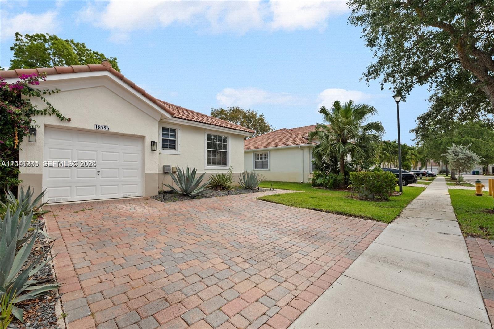 A single-story house with a white stucco facade, tiled roof, and a brick paver driveway — 18755 SW 27th Ct, Miramar FL 33029, MIRAMAR, FL