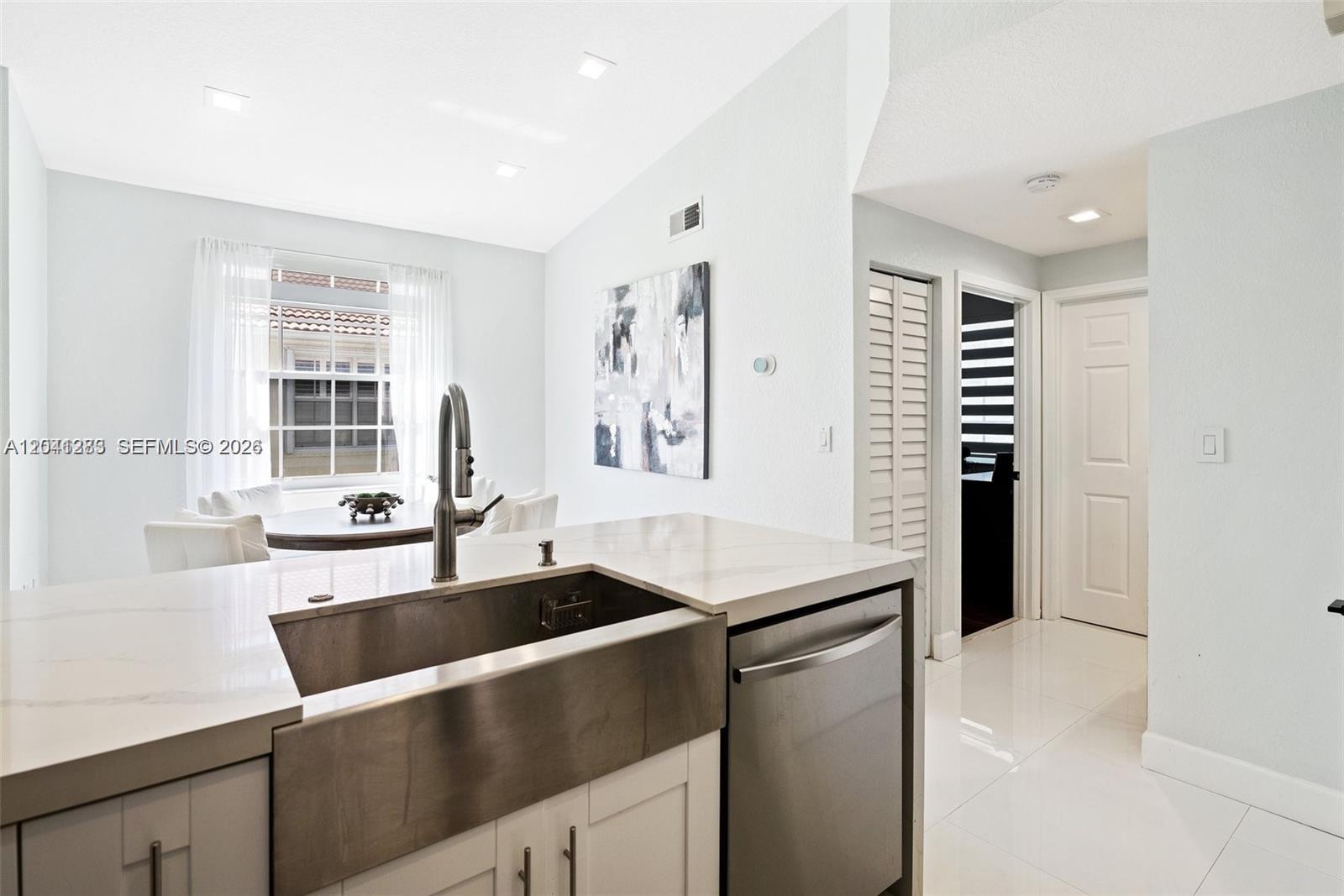 A kitchen features a stainless steel farmhouse sink, white countertops, and a dining area nearby — 18755 SW 27th Ct, Miramar FL 33029, MIRAMAR, FL