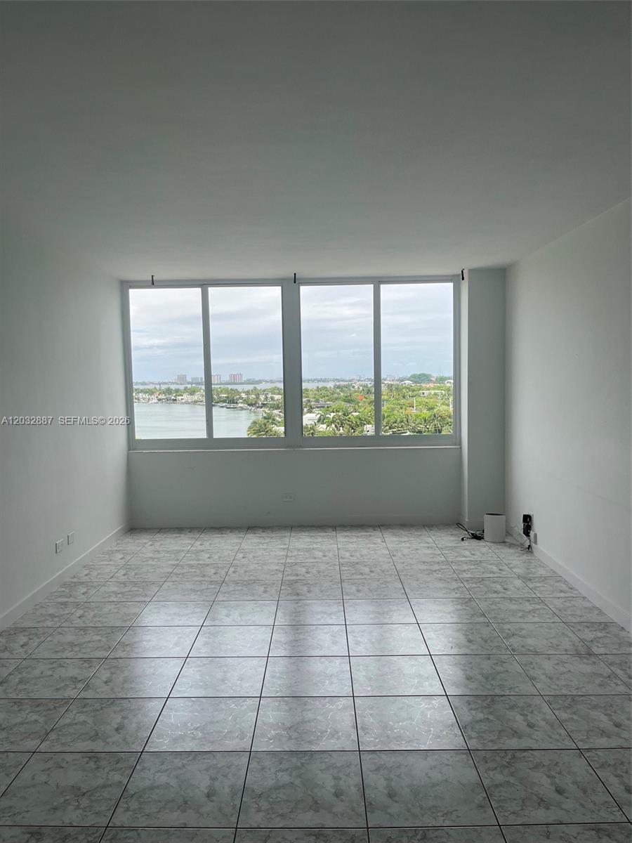 An empty room features white walls, gray marble-patterned tile flooring, and a large window view — 7441 Wayne Ave # 8B, Miami Beach FL 33141, MIAMI BEACH, FL