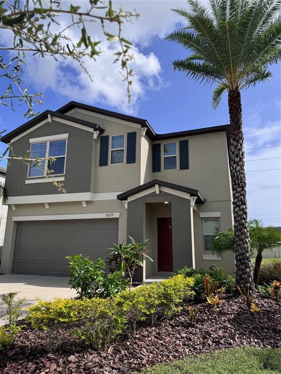 A two-story house with a garage, a red front door, and a tall palm tree — 5059 WHITE CHICORY DRIVE, APOLLO BEACH, FL