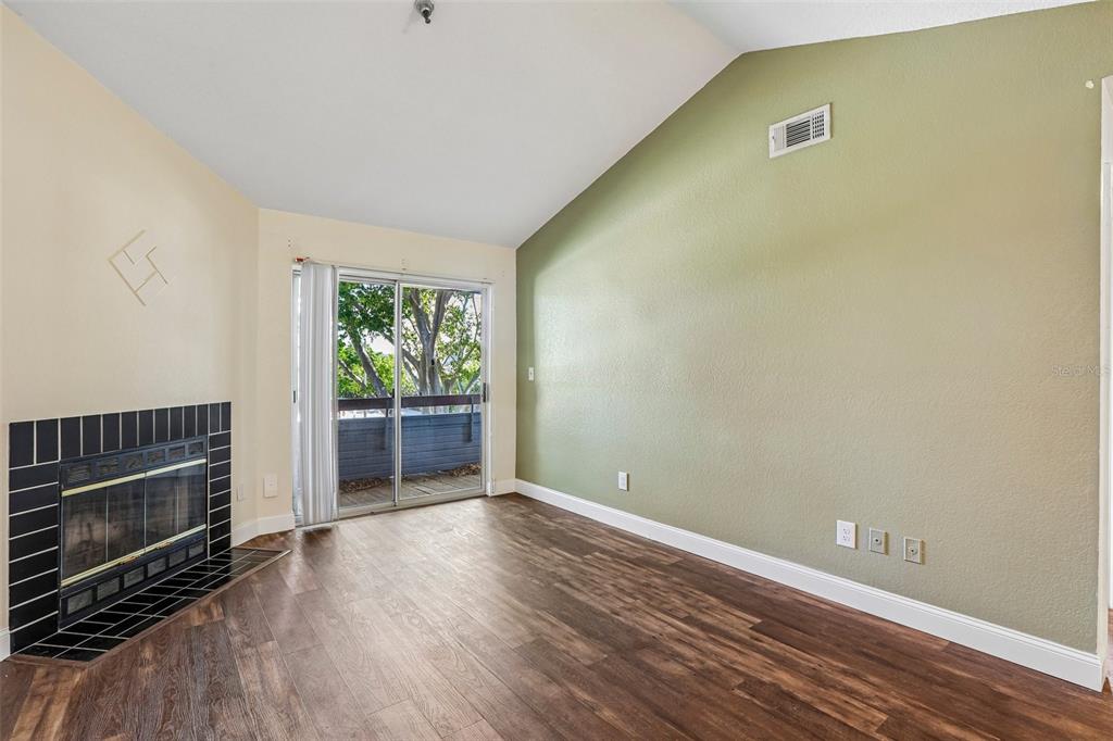 A living room features wood-look flooring, a black-tiled fireplace, and a sliding glass door — 10263 GANDY BOULEVARD N UNIT 406, ST PETERSBURG, FL