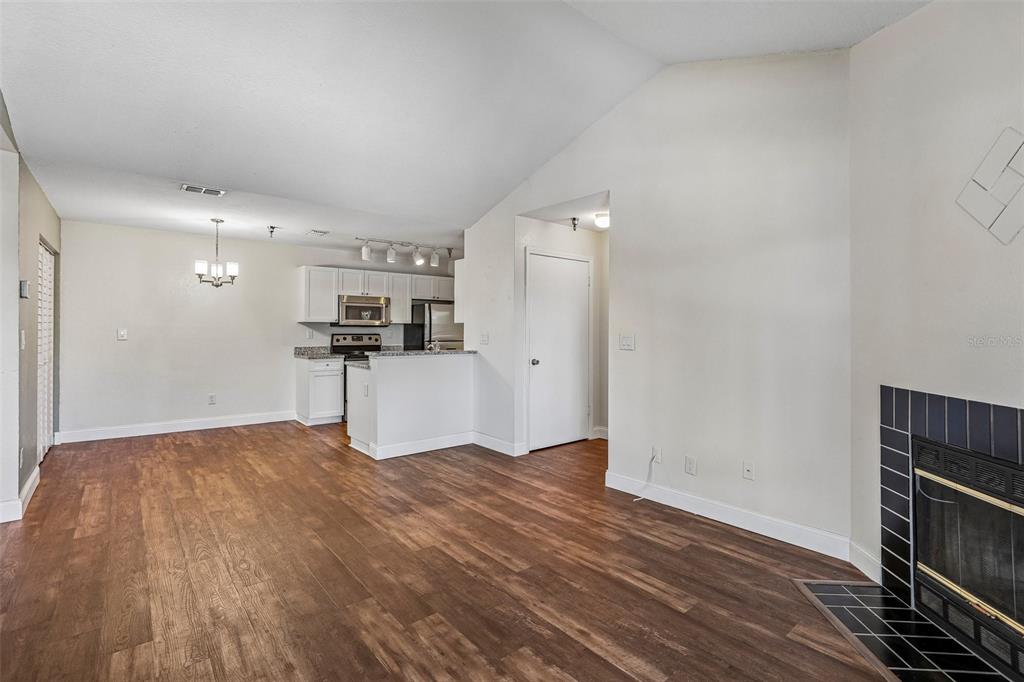 A living room with wood-look flooring and a fireplace leads to an open kitchen area — 10263 GANDY BOULEVARD N UNIT 406, ST PETERSBURG, FL