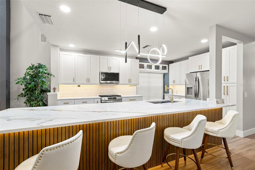 A kitchen features white cabinets, gold hardware, a gas range, and a white picket-style backsplash — 9915 HARTWELL BRIDGE CIRCLE, TAMPA, FL