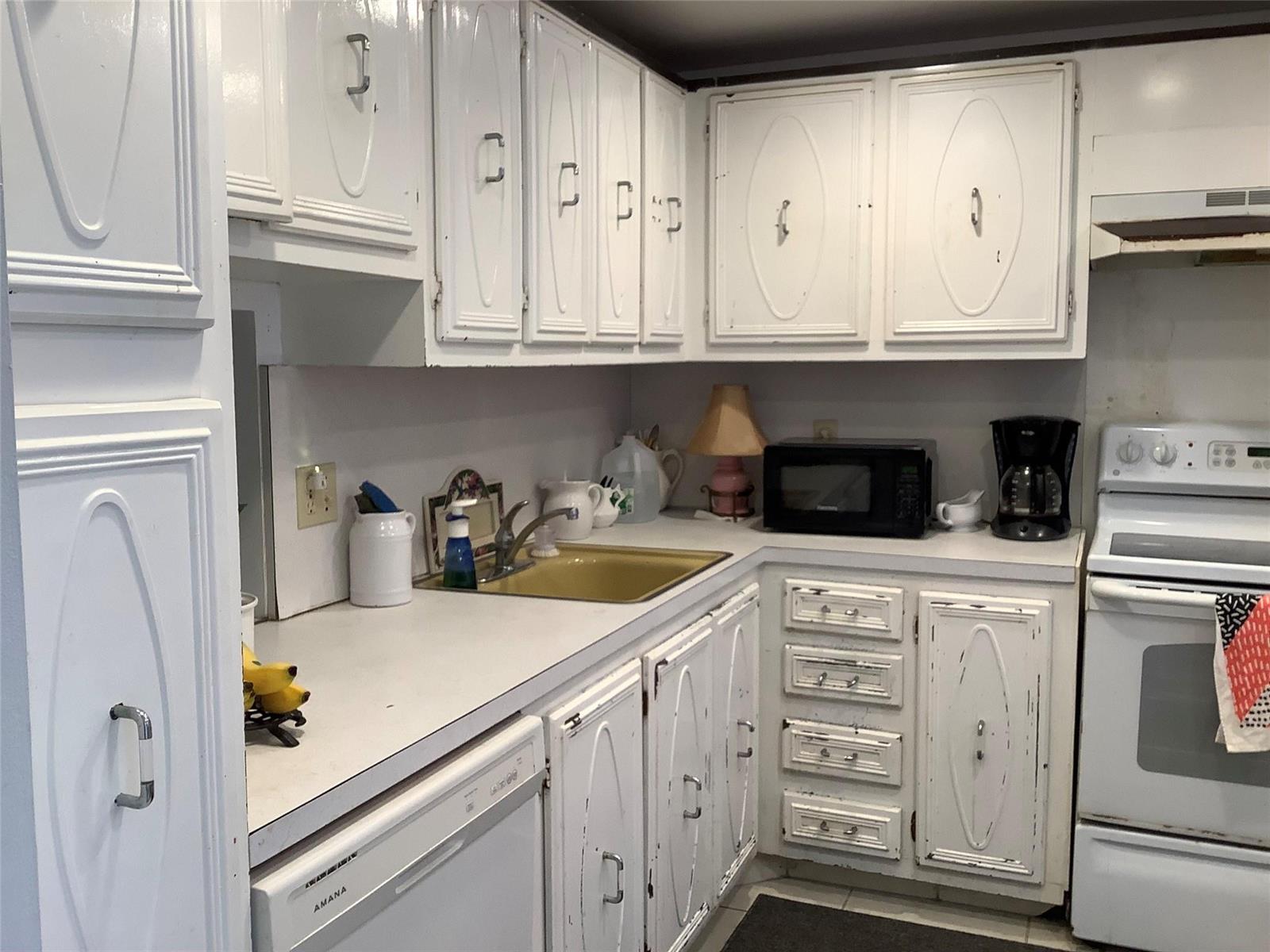 A kitchen features white cabinets, a gold sink, a microwave, and a white stove — 2300 NE 1st Lane # 107, Boynton Beach FL 33435, BOYNTON BEACH, FL