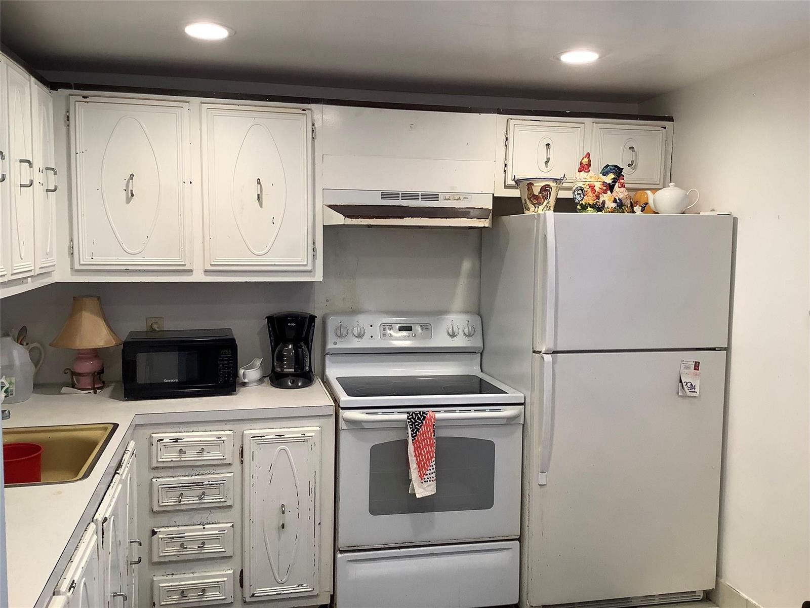 A kitchen features white cabinets, a white stove, a white refrigerator, and a small microwave — 2300 NE 1st Lane # 107, Boynton Beach FL 33435, BOYNTON BEACH, FL